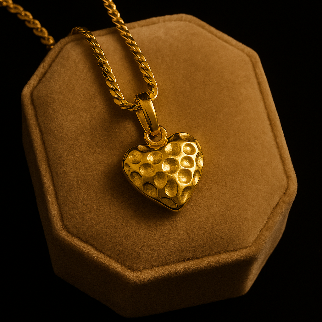 Gold heart-shaped pendant on a chain displayed on a brown velvet stand against a black background