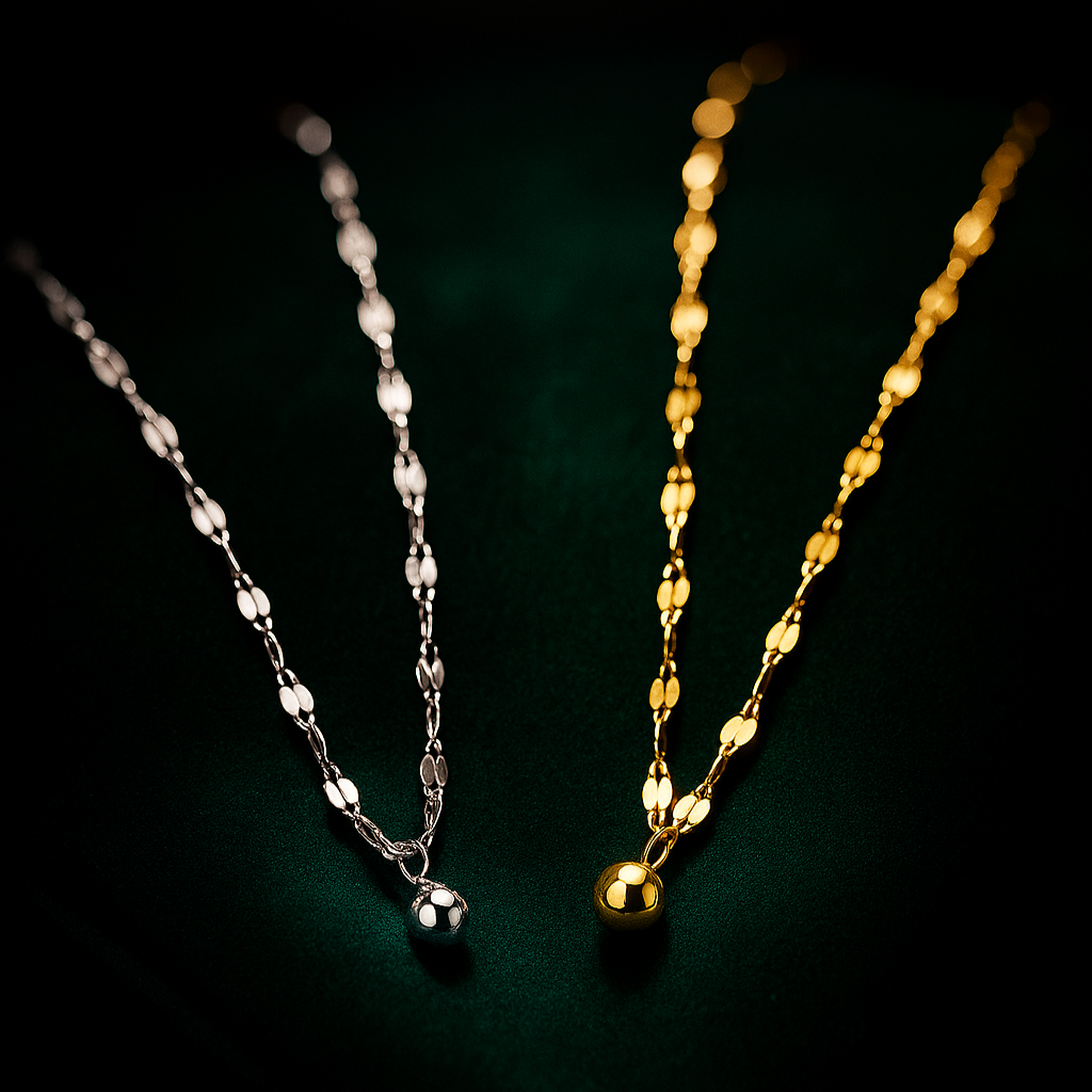 Two necklaces, one silver and one gold, on a dark background