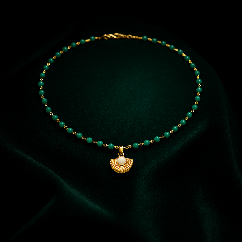 Gold necklace with green beads on a dark fabric background