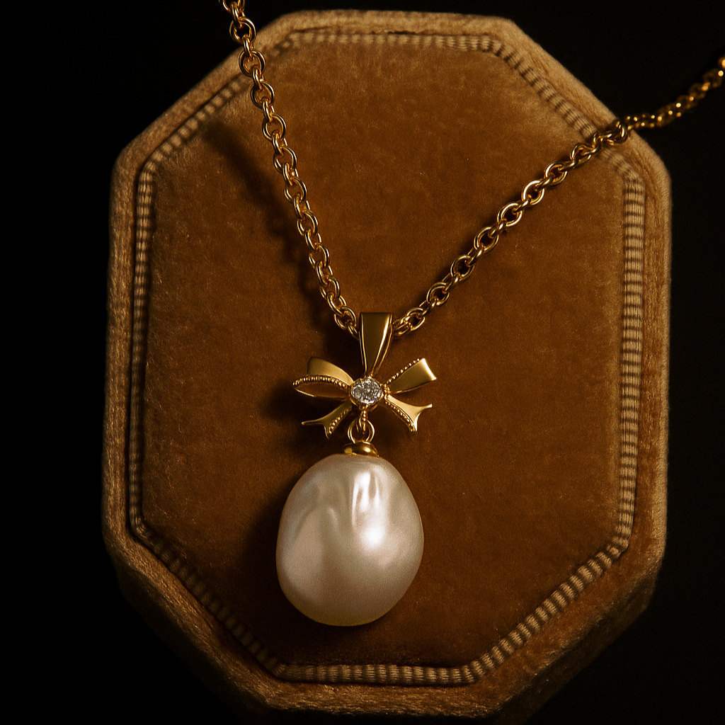 Pearl pendant with gold bow on a necklace, displayed on a brown velvet stand against a black background.