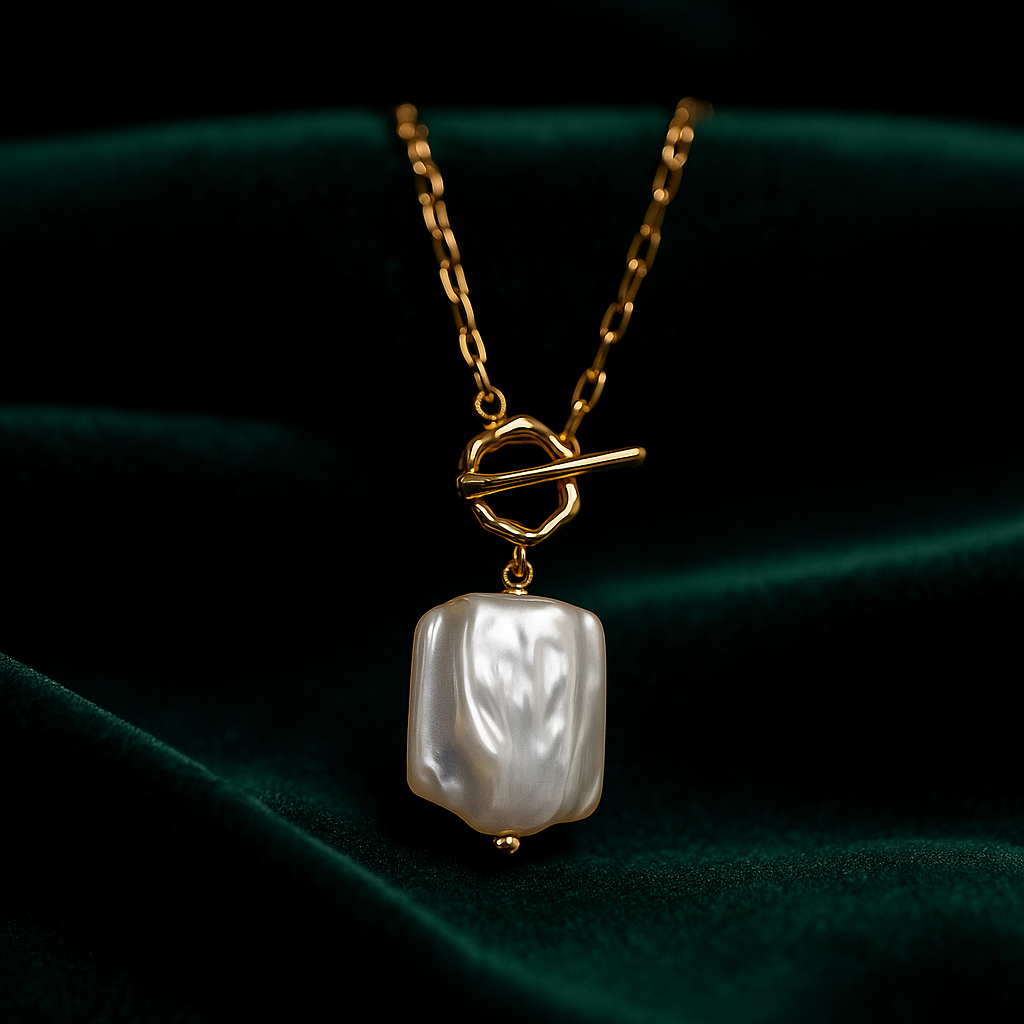 Gold necklace with a baroque pearl pendant on a dark green fabric background
