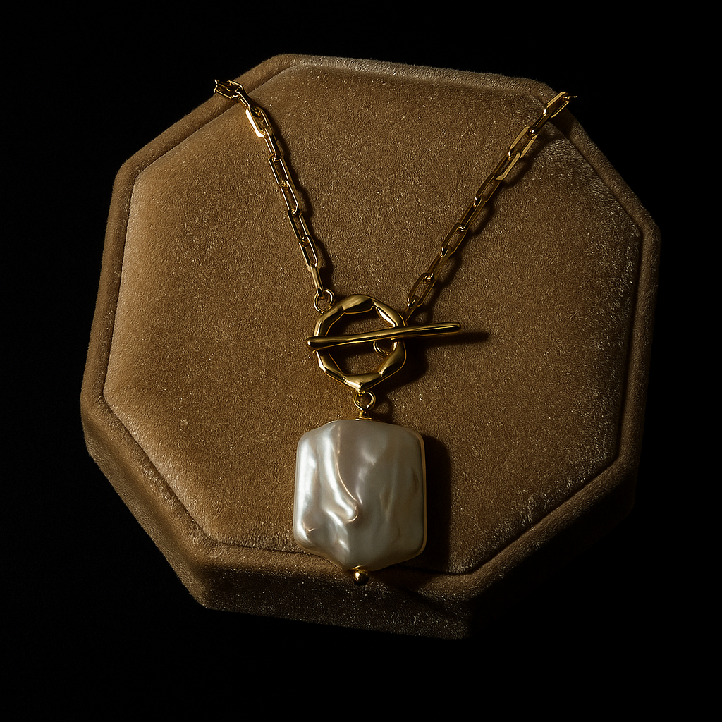 Gold necklace with a large pearl pendant on a brown hexagonal display stand against a black background.