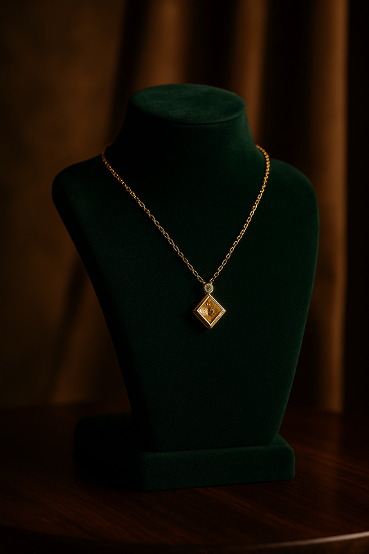 Gold necklace with a pendant on a green velvet stand against a dark background