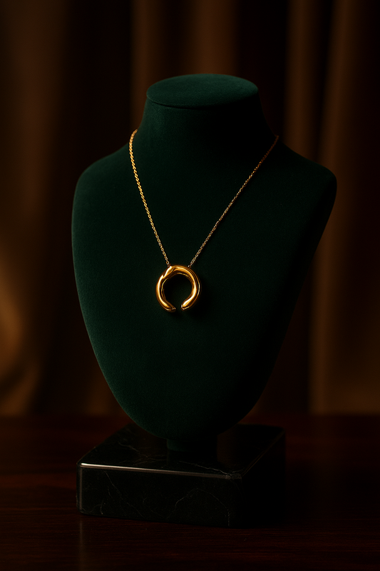Gold necklace on a green velvet mannequin bust against a dark background