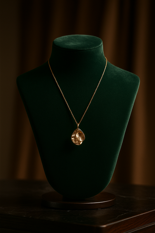Gold necklace on a green velvet mannequin bust against a dark background