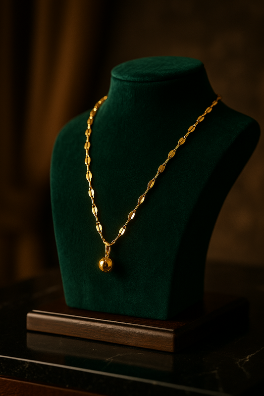 Gold necklace on a green velvet mannequin bust with a dark background