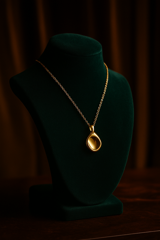 Gold necklace with a pendant on a green velvet mannequin against a dark background