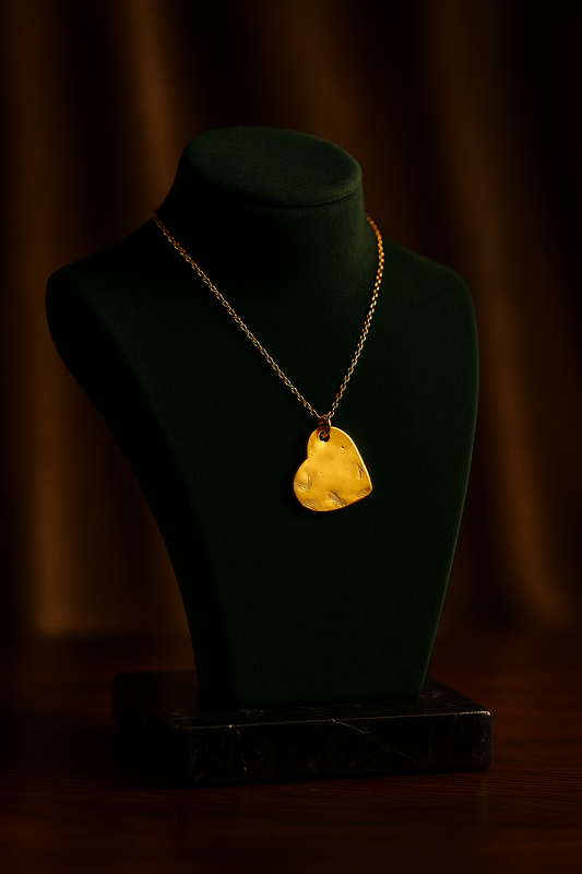 Gold necklace with a yellow pendant on a green mannequin bust against a dark background