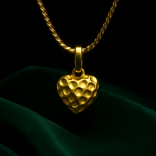 Gold heart-shaped pendant on a chain against a dark background