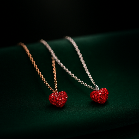 Three necklaces with red heart pendants on a dark green surface.