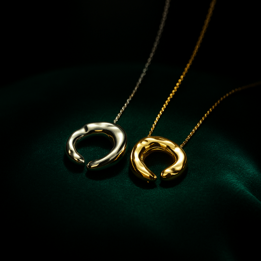 Two gold necklaces with circular pendants on a dark background