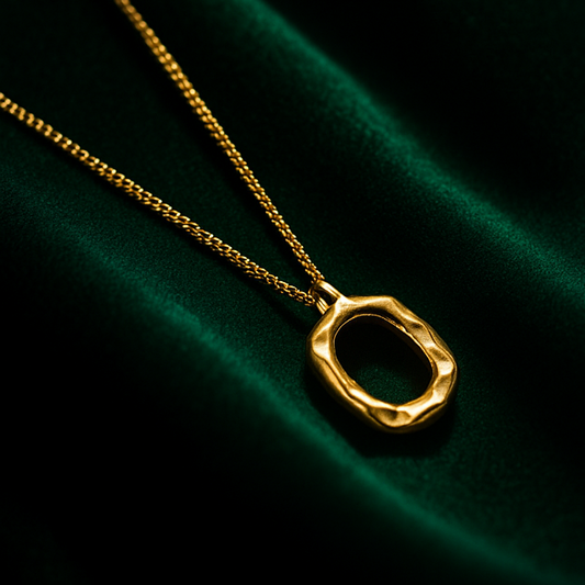 Two necklaces with unique circular pendants on a dark green fabric background