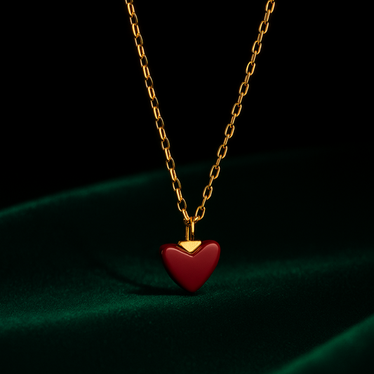 Gold chain necklace with a red heart pendant on a dark background
