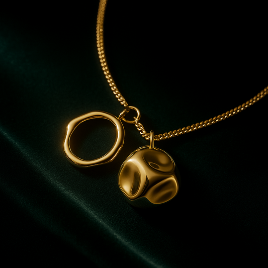 Gold necklace with two pendants on a dark background