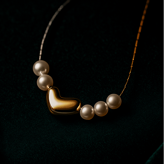 Two necklaces, one silver and one with pearls and gold accents, on a dark background.