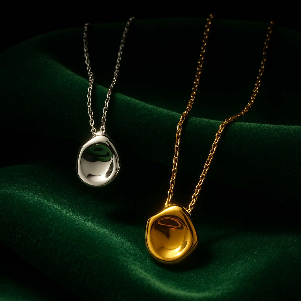 Two necklaces with pendant stones on a dark green fabric background