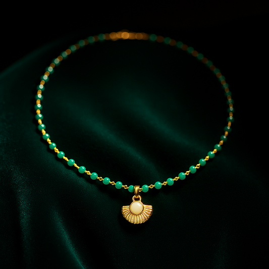 Necklace with green beads and gold pendant on a dark green fabric background