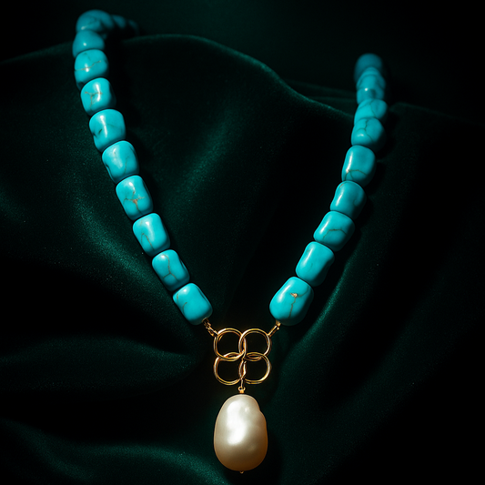 Turquoise beaded necklace with a pearl pendant on a dark fabric background